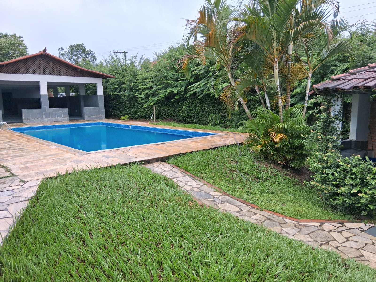 Piscina ampla da unidade cercada por árvores e jardim