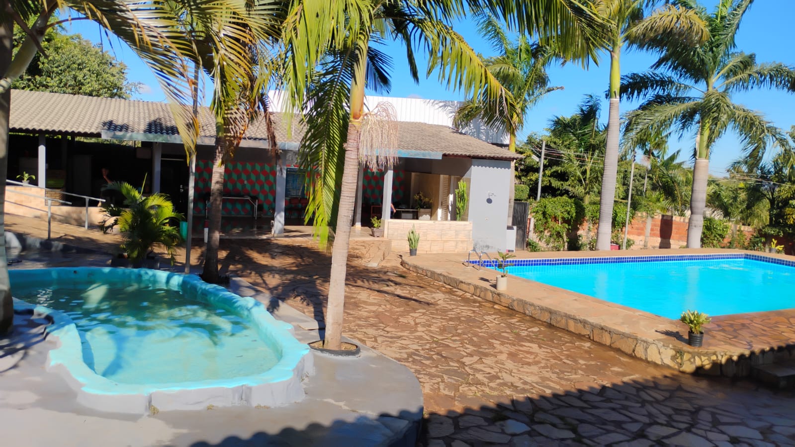 Área de lazer com piscinas, coqueiros e espaço de convivência