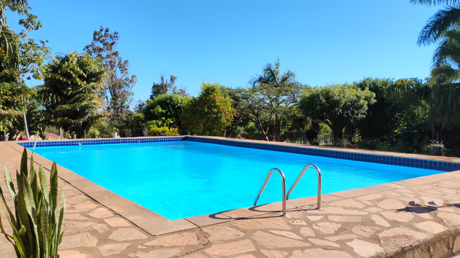 Piscina com quiosque, gramado e jardim bem cuidado